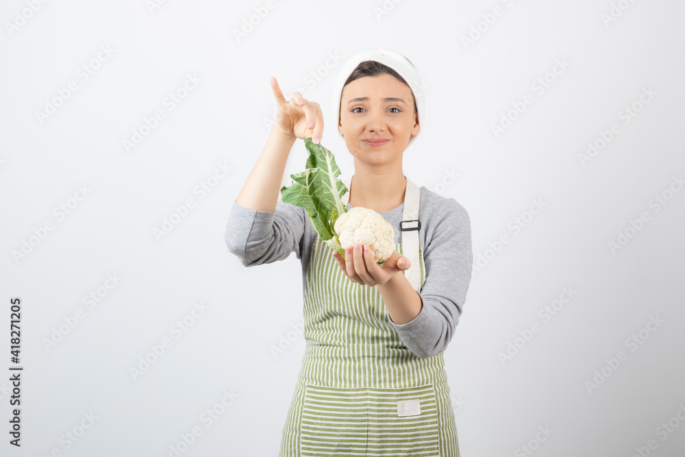 Photo of a young nice woman model in apron holding a cauliflower Photo of a young nice woman model in apron holding a cauliflower