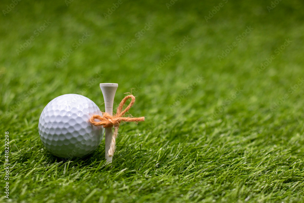 Fototapeta premium Golf ball and tee are on green grass