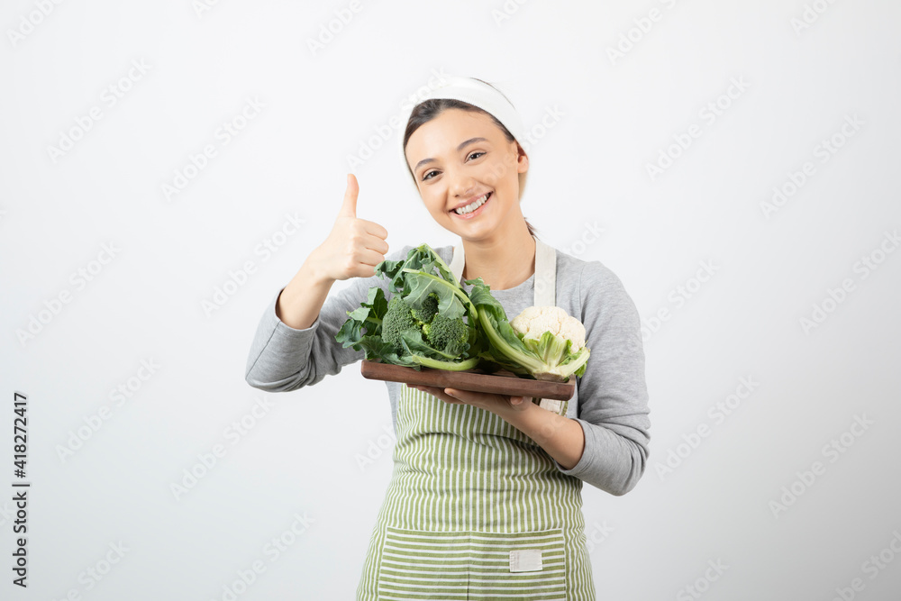 Picture of a smiling attractive woman with a wooden plate of cauliflowers Picture of a smiling attractive woman with a wooden plate of cauliflowers