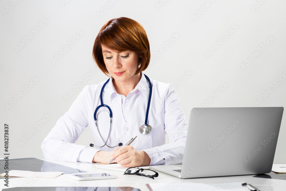 Beautiful doctor sitting in office and writing Beautiful doctor sitting in office and writing