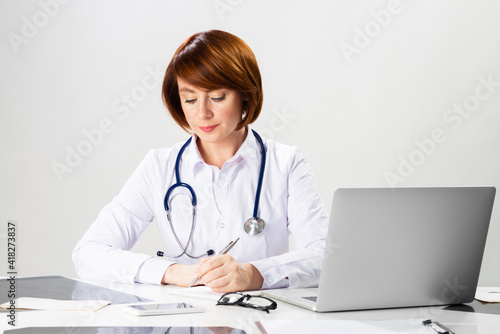 Beautiful doctor sitting in office and writing