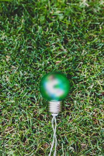 green light bulb on perfect green grass lawn, ecology and sustainability © faithie