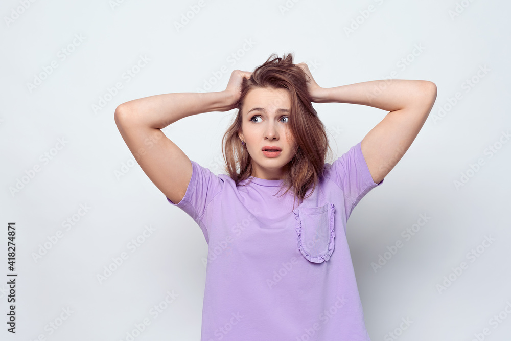 Portrait of girl in casual t shirt in panic grabbing her head in fear or frustration. Stress and mental health Portrait of girl in casual t shirt in panic grabbing her head in fear or frustration. Stress and mental health
