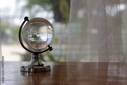 Glass world globe on a shelf in front of a garden window