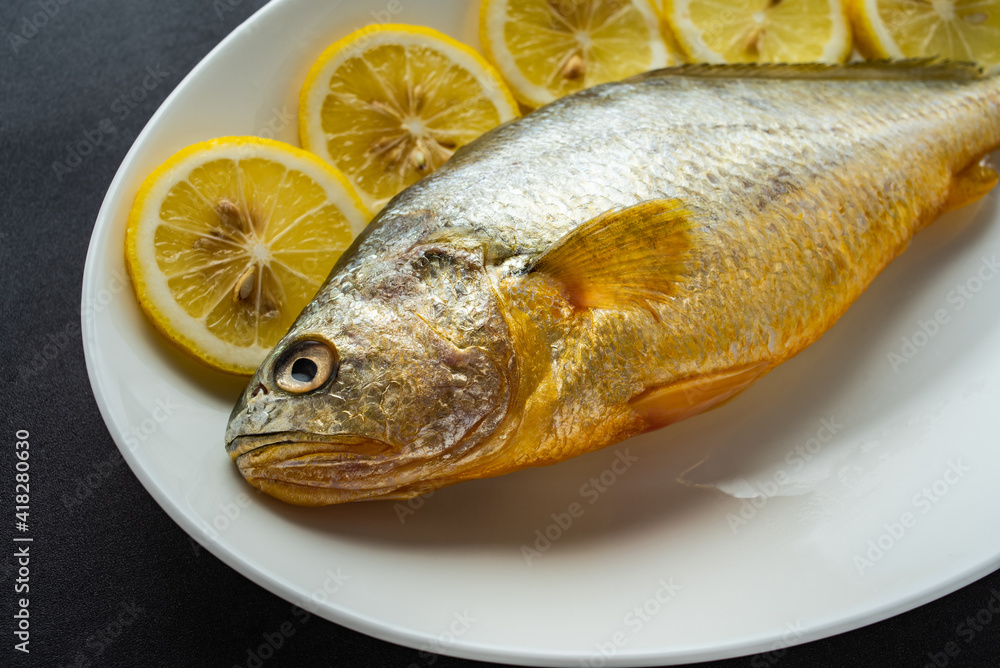 A fresh yellow croaker on a white plate