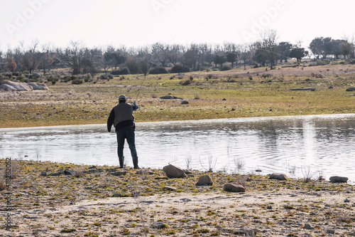 A man dressed in brown casts his fishing rod to catch fish