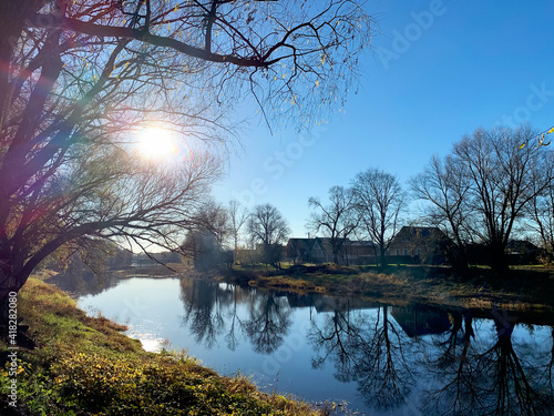 Rural landscape with a river and old wooden houses. Sunny autumn day. Poster, postcard. Background for your design.