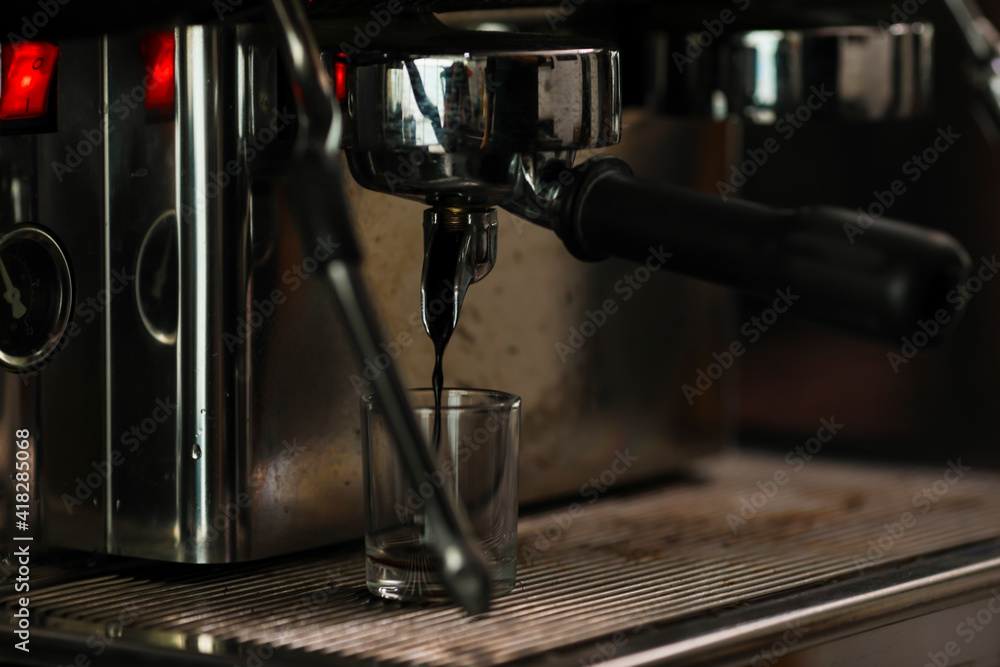 Close up shot of measuring glass filling with dark brown hot delicious good smell coffee by luxury clean steel coffee making machine in cafe with blurred background Close up shot of measuring glass filling with dark brown hot delicious good smell coffee by luxury clean steel coffee making machine in cafe with blurred background