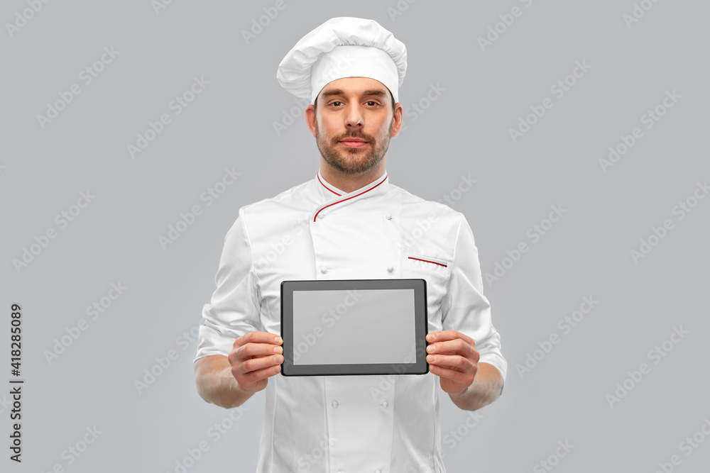 cooking, culinary and people concept - male chef in toque showing tablet pc computer over grey background cooking, culinary and people concept - male chef in toque showing tablet pc computer over grey background