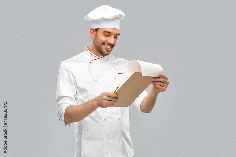 cooking, culinary and people concept - happy smiling male chef with clipboard and pencil over grey background cooking, culinary and people concept - happy smiling male chef with clipboard and pencil over grey background