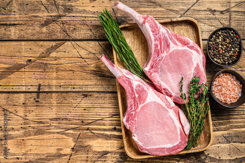 Fresh raw pork loin chops with pepper and salt. wooden background. Top view. Copy space photo