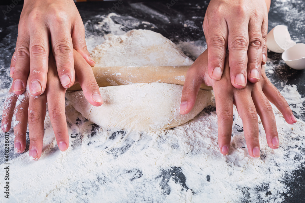 Fototapeta premium Mother and daughter hands stretching dough with a rolling pin.