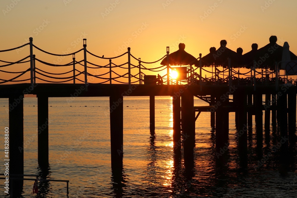 The silhouette of the pier against the background of the sunset and the Mediterranean sea