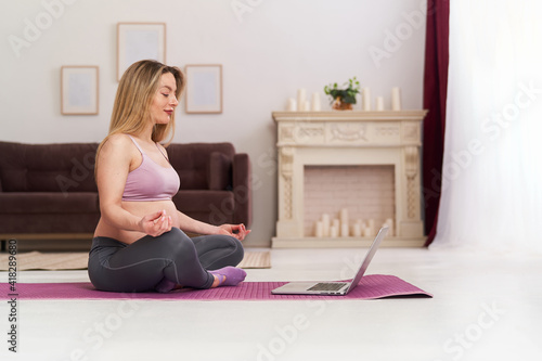 Happy attractive pregnant woman in sports clothes, doing exercises on the gym mat at home in the living room. health during pregnancy. yoga classes at home. Motherhood, active pregnancy.
