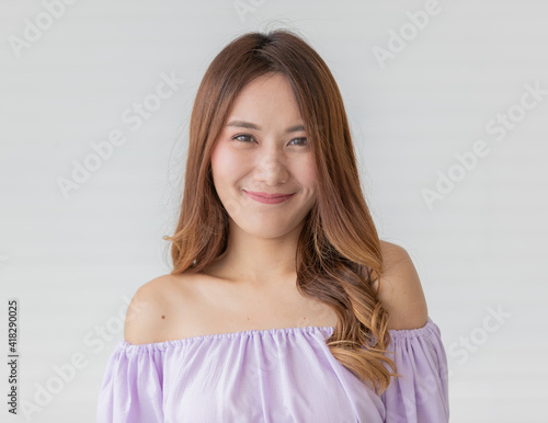 Portrait close up shot of young pretty asian female with long brown hair wearing light purple long sleeve shirt stand smiling with self-confidence to camera in front of white background
