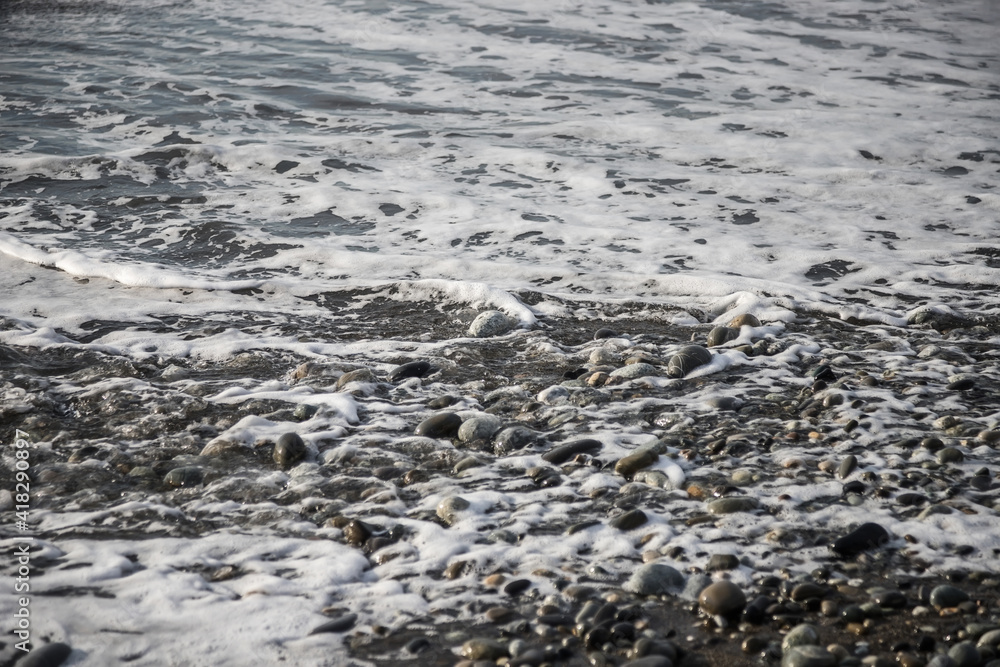 Sea shore with stones and foam, pebble seascape. 