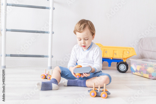 baby boy playing with wooden toys at home on the floor