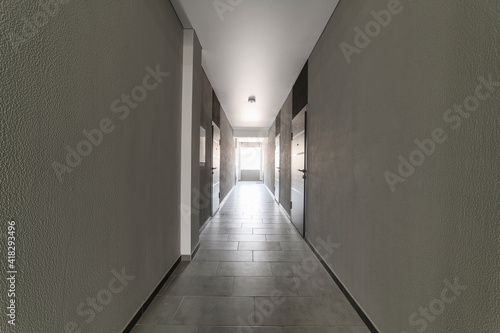 Grey corridor with doors and lights at the end