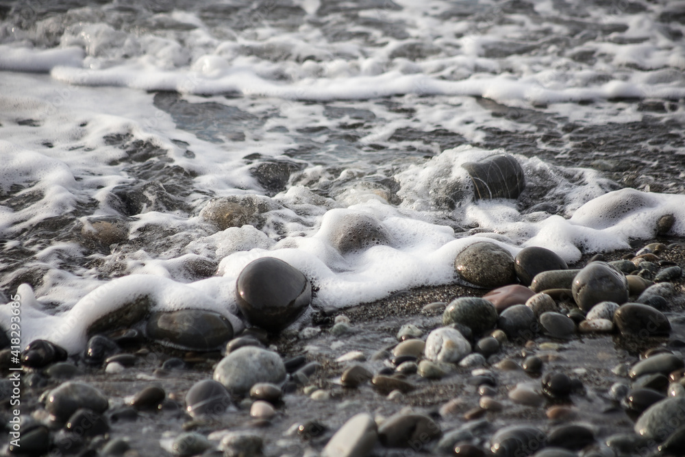 Sea shore with stones and foam, pebble seascape. 