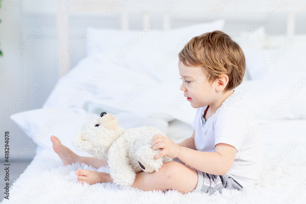 baby with a teddy bear on the bed at home playing