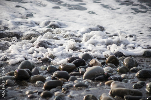 Sea shore with stones and foam, pebble seascape. 