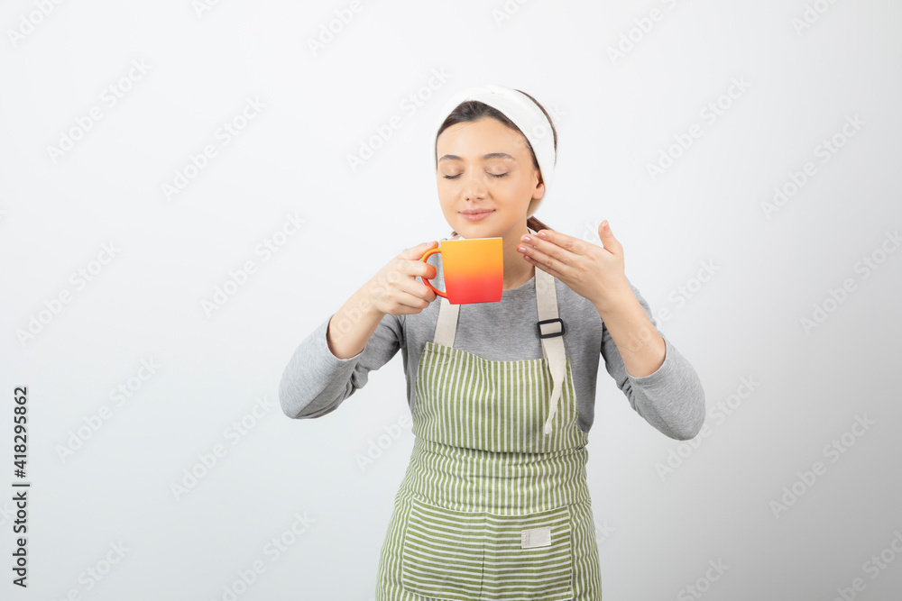 Image of a pretty young woman in apron holding a cup Image of a pretty young woman in apron holding a cup
