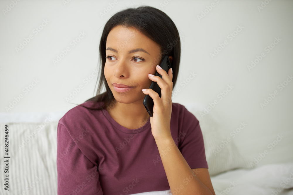 Technology, connection and communication concept. Isolated image of beautiful young African American female having thoughtful dreamy facial expression, speaking on smart phone with boyfriend Technology, connection and communication concept. Isolated image of beautiful young African American female having thoughtful dreamy facial expression, speaking on smart phone with boyfriend