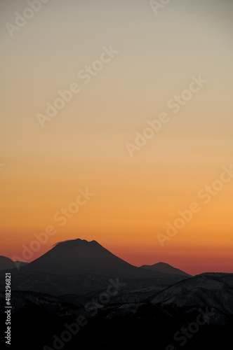 オレンジ色の夕暮れの空と山並みのシルエット。 © Masa Tsuchiya