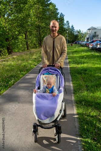 dad and little toddler son walk in the park in the spring