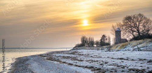 Fototapeta Naklejka Na Ścianę i Meble -  Panorama des natürlichen Strandes am Abend mit warmem Abendlicht mit einem alten Leuchtturm