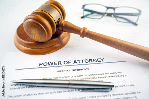 power of attorney text on contract with pen, gavel and glasses as props. photo