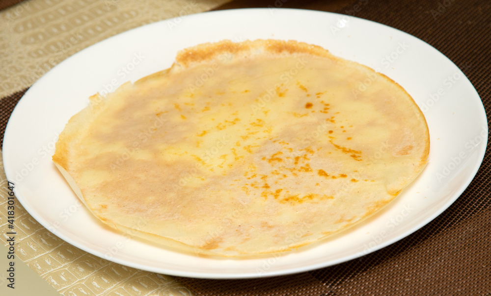 delicious round pancake lies on a white plate