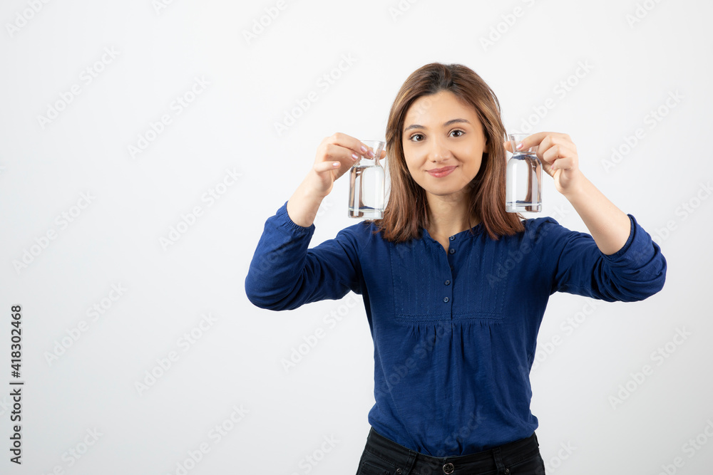 Beautiful woman in blue blouse holding glass of water on white background