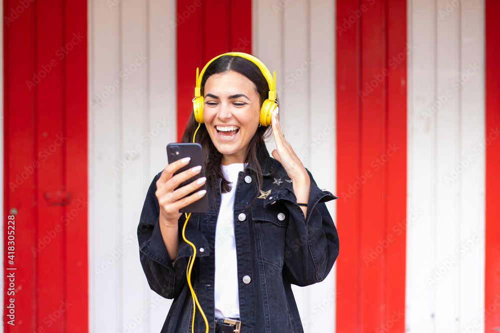 Young brunette woman smiling happy using smartphone and headphones at the city. Young brunette woman smiling happy using smartphone and headphones at the city.