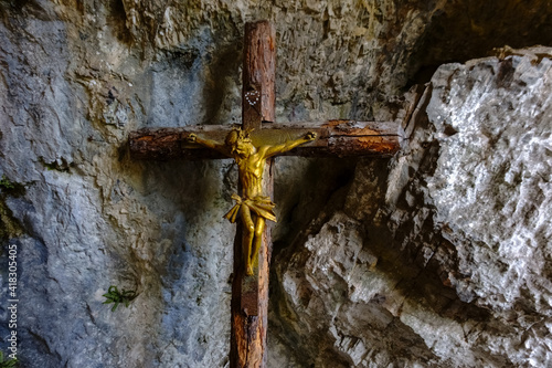 very old cross made of wood with jesus in a cave