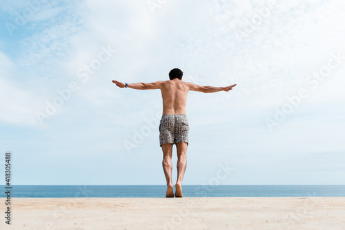 Man with arms raised to jump into the water