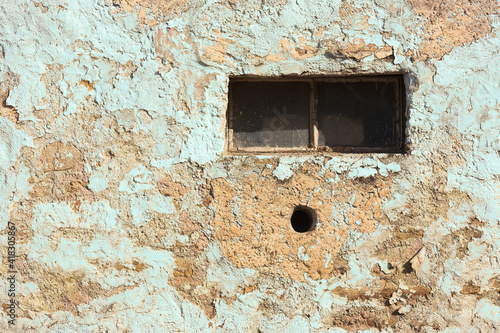 Old abandoned building with a small window and hole resembling face saying oh and paint peeling off © Yann Wirthor