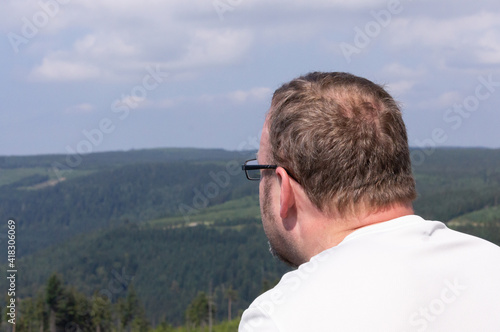Man with a white t-shirt land glasses looking at the landscape