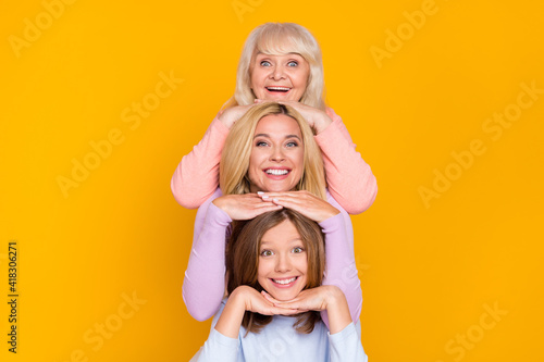 Photo of nice optimistic three woman grand mom daughter hands face wear pastel cloth isolated on yellow color background photo