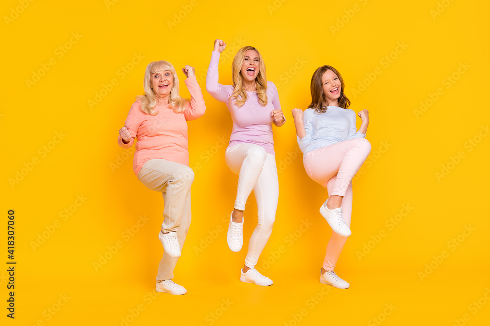 Fototapeta premium Photo of hooray three woman grand mom daughter hands fists wear pastel cloth isolated on yellow background