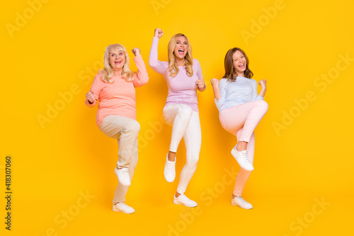 Photo of hooray three woman grand mom daughter hands fists wear pastel cloth isolated on yellow background