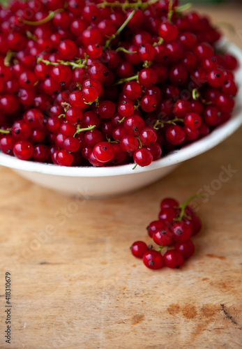 Currants in a bowl on a wooden background. Red berry. Vitamin berries. Copy space