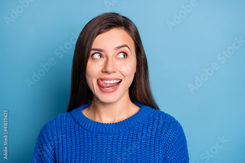 Portrait of young cheerful positive smiling good mood girl look copyspace lick lip with tongue isolated on blue color background