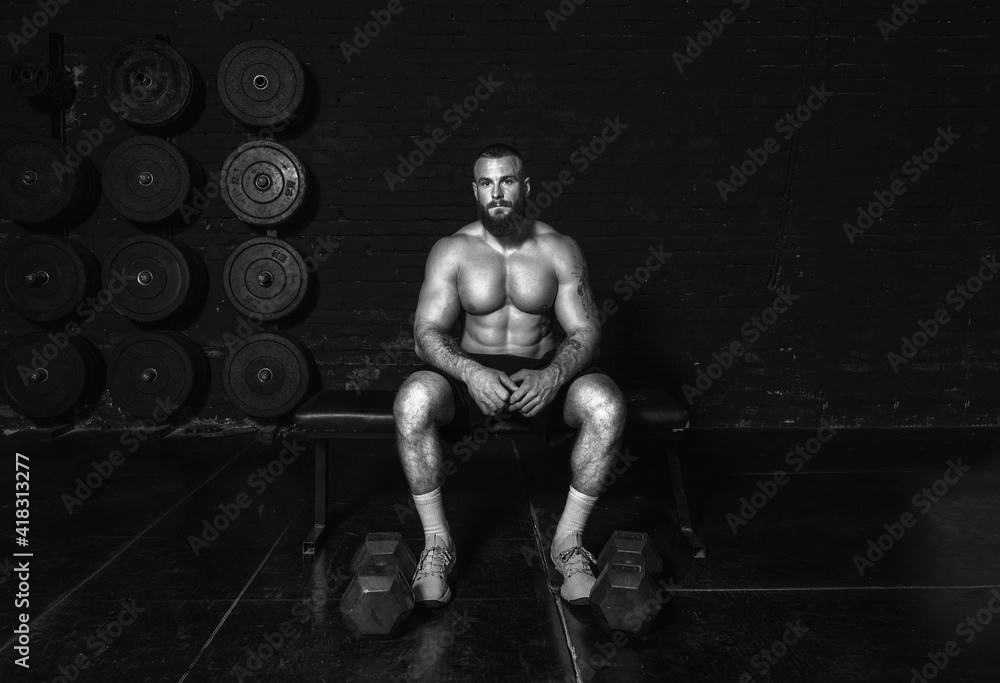 Young active strong sweaty muscular fit man with big muscles sitting in the gym taking a break after hardcore workout training real people exercise Young active strong sweaty muscular fit man with big muscles sitting in the gym taking a break after hardcore workout training real people exercise