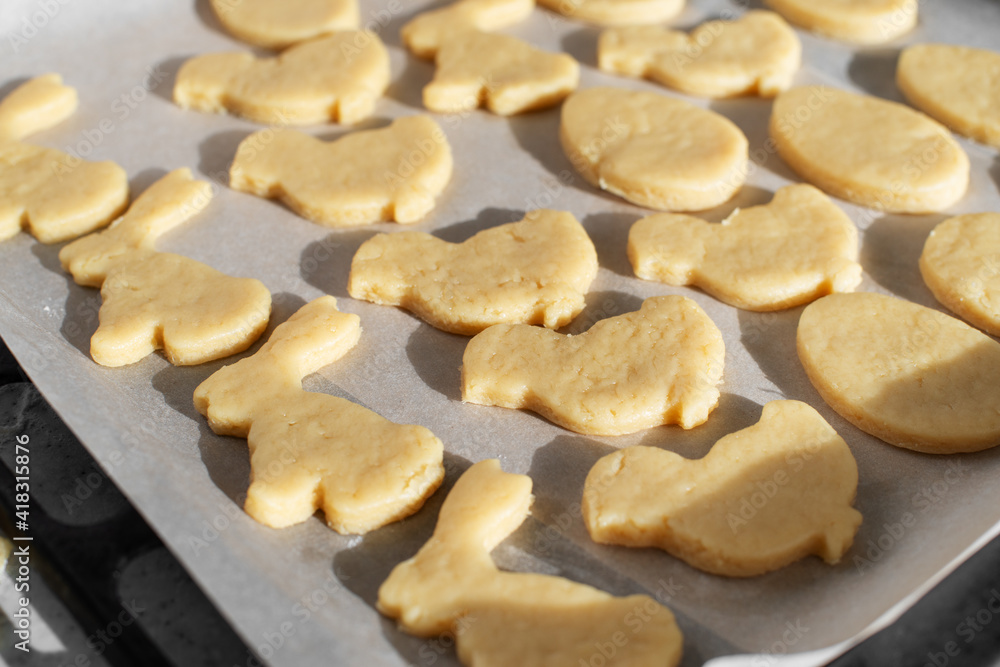 Ready for baking cookies cut in shape of rabbit, egg and chicken on parchment paper Ready for baking cookies cut in shape of rabbit, egg and chicken on parchment paper