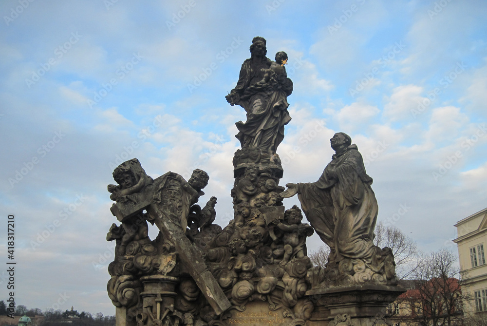 Religious stone sculptures of the Charles Bridge in Prague on a cloudy day.