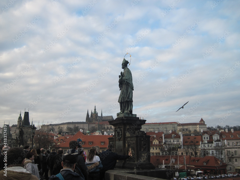 Religious stone sculptures of the Charles Bridge in Prague on a cloudy day.