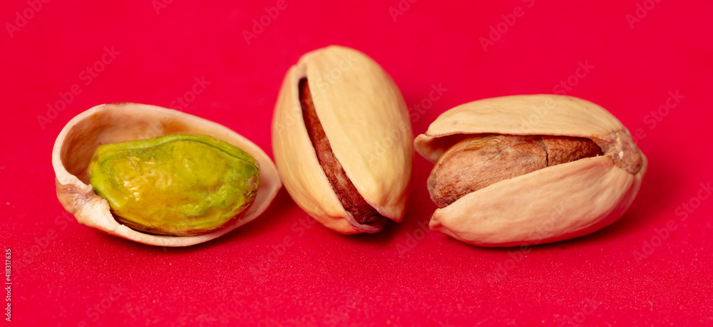 Fototapeta premium Close-up of fresh pistachio nuts on a red background.
