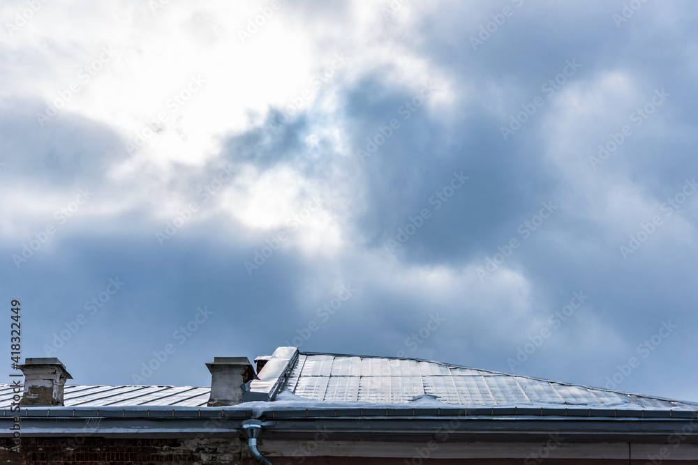 Fototapeta premium Clearance in the cloudy sky above the metal roof of the building.