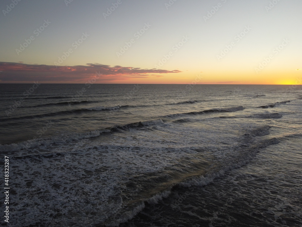 sunset in the atlantic ocean coast of argentina monte hermoso. waves with foam and beautiful sky colors